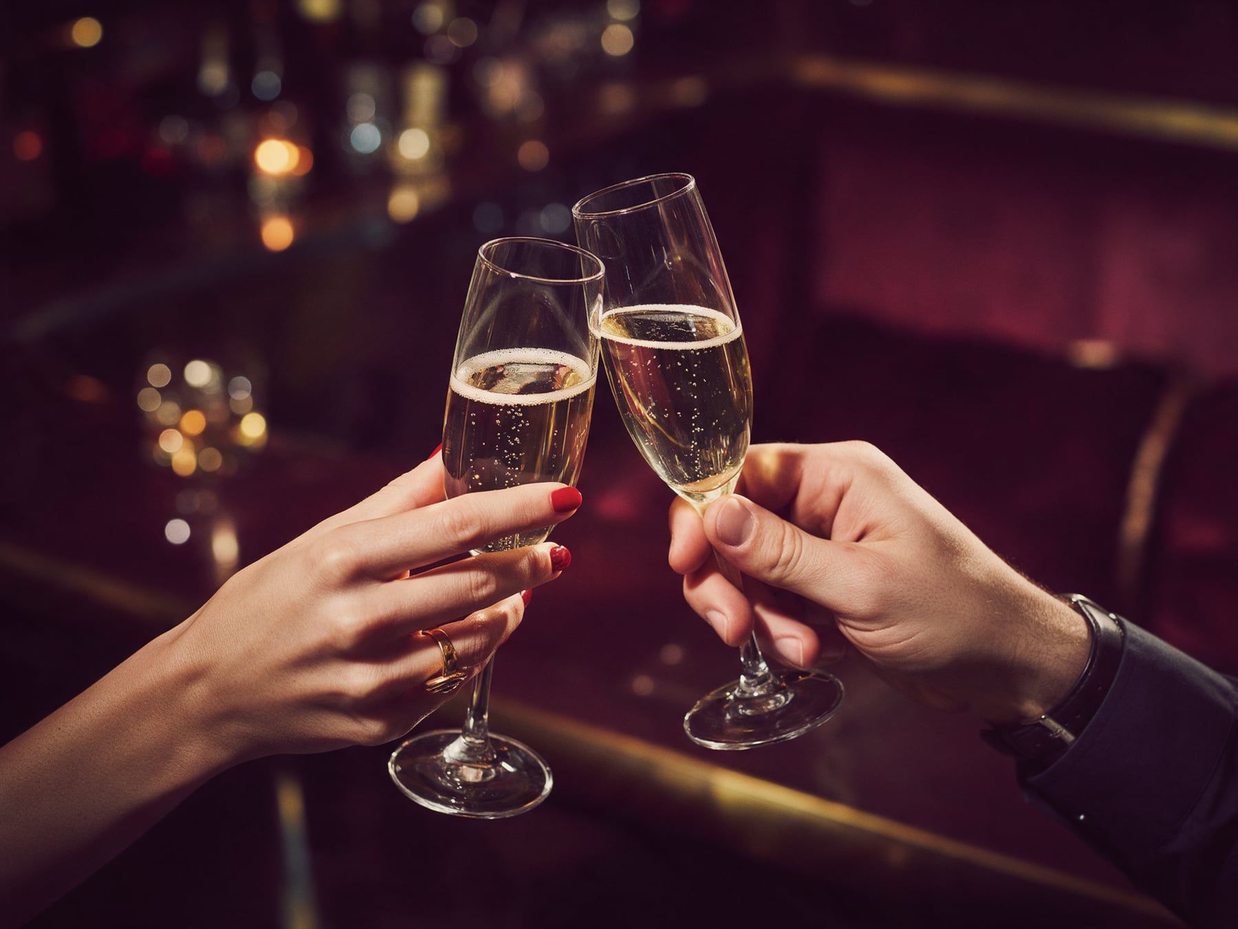 Deux mains trinquent avec des coupes de champagne dans un bar tamisé